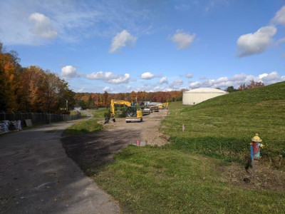 view of work area, hydrant in forground, excavator and water tank in background