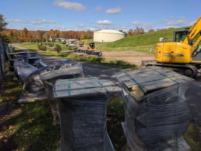 nine stacks of Materials Stockpile and Erosion Control in forground, crawler
                excavator to left center and water tower in center background
