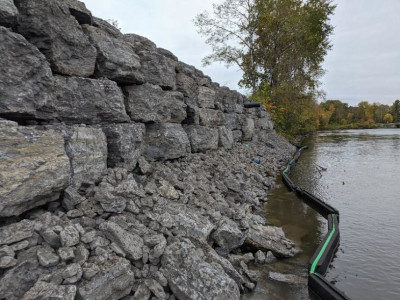 view of newly built wall on left, sediment curtain in water, water on right