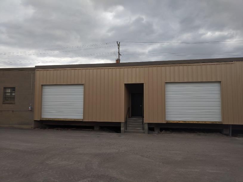 Tan building with two large white garage doors on opposite sides of cut-out entry way in center