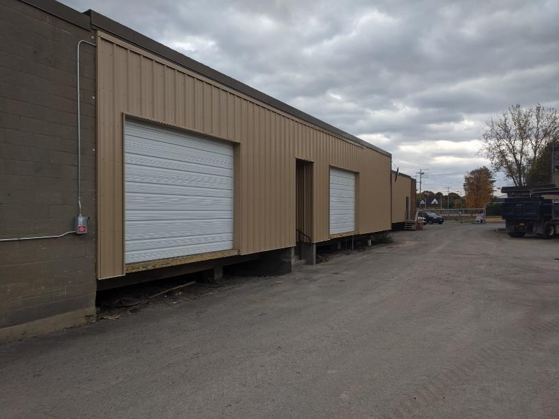 long angle shot of loading dock on left, drive way on right, trees in background