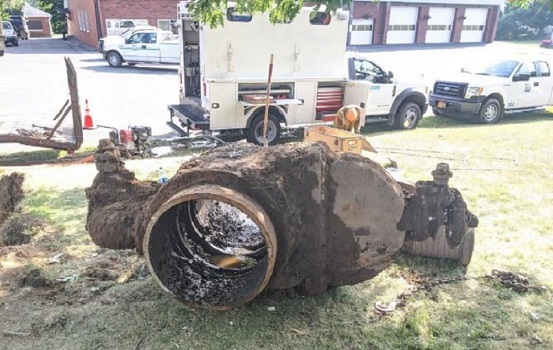 very old, soiled covered gate valve 
                    in foreground, MVWA trucks in bacKground