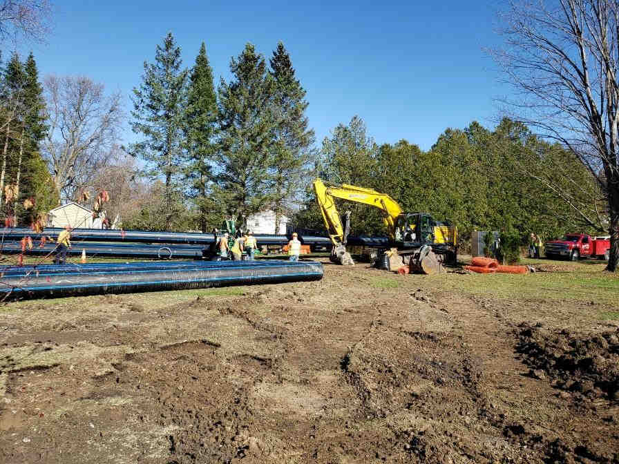 pan-out view of area with pipes, people and backhoe