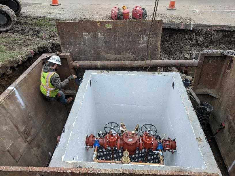 in the pit, man outside the chamber with open view of valves inside chamber