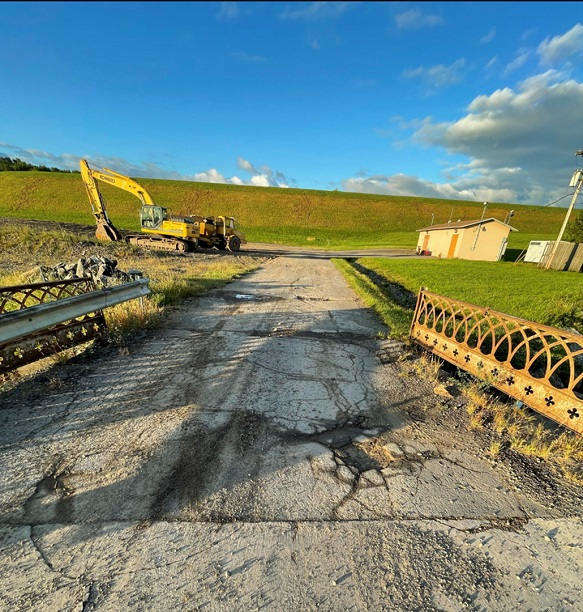 brige with cracks, railings, earth moving equipment in background