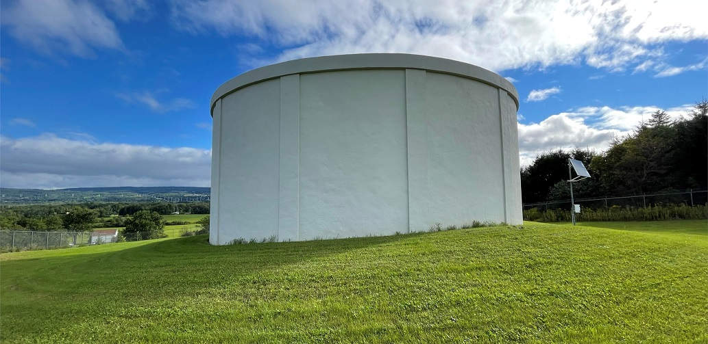 finished white water tank on top of green hill, blue sky