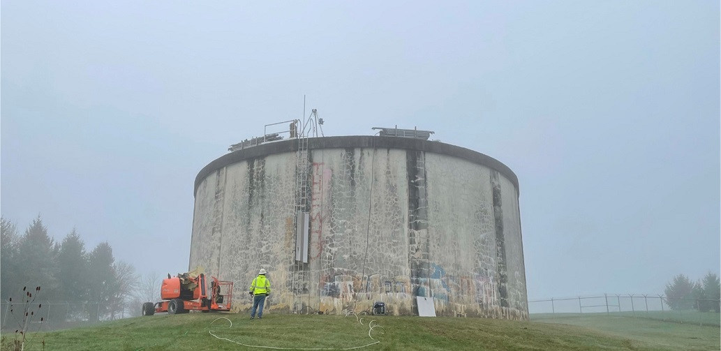 man looking up the outside of water tank at start of project