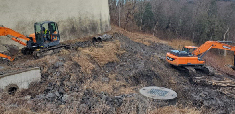 backhoe and excavator working near tank and drain cover